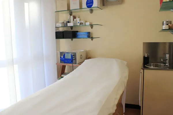 Cabina per trattamenti viso in ordine, con lettino e mensole