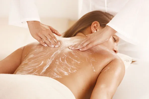 Applicazione di uno scrub sulla schiena durante un trattamento corpo